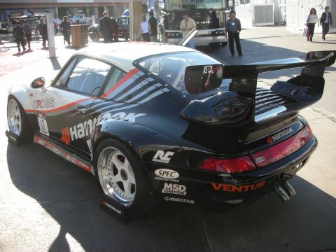 1998 Ford Crown Victoria - Side rear view of a black and white Porsche 911 race car with a tall adjustable rear wing and Hankook sponsor decals.