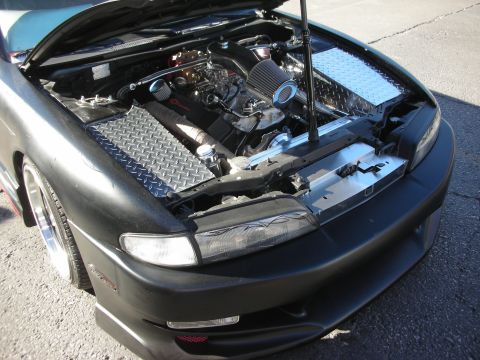1998 Ford Crown Victoria - open engine bay of a matte-black sports coupe shows a swapped engine, cone air filters and diamond-plate covers.