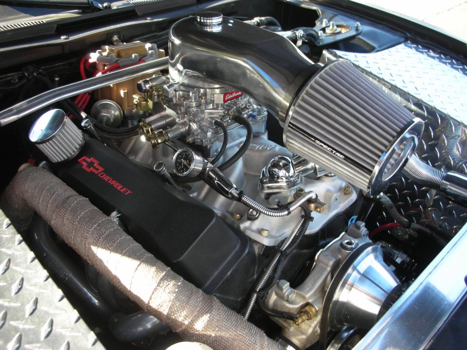 Chrome V8 engine with Edelbrock carb and cone filter under a car hood