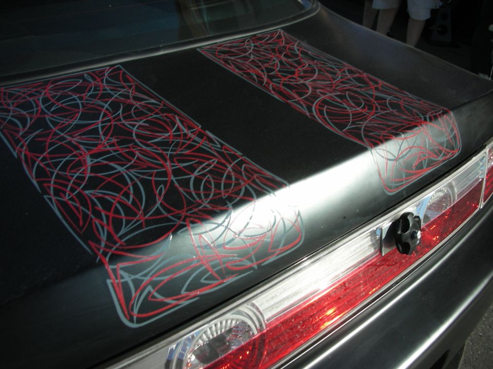 Close-up of red and silver pinstripe artwork on a dark car trunk lid