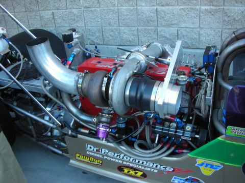 1998 Ford Crown Victoria - polished turbocharged diesel engine sits in a rail dragster lettered Dr. Performance Diesel Specialists.