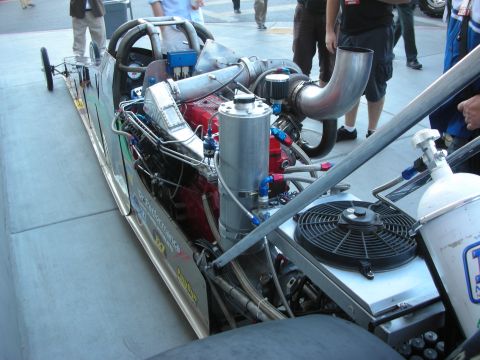 1998 Ford Crown Victoria - long narrow rail dragster shows its mid-mounted diesel engine, turbo piping and cooling fan from the side.