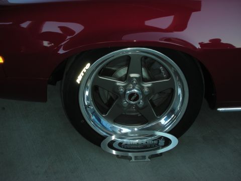 1998 Ford Crown Victoria - polished gray five-spoke wheel wrapped in a Nitto tire sits under the red fender of a show car.