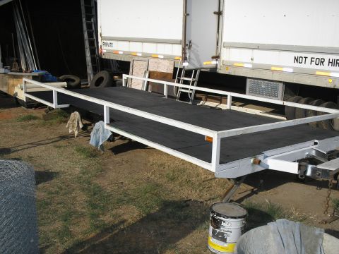 1990 Ford Bronco - A trailer with a ramp is parked next to a large truck, with various items scattered in the yard.