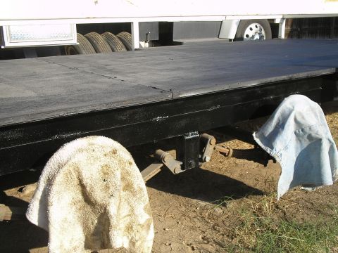 1990 Ford Bronco - A trailer's undercarriage is visible, with spare tires and a hitch covered by cloth.