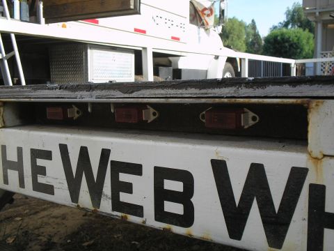 1990 Ford Bronco - Close-up of a trailer with three red lights and partial black lettering that reads "HE WEB WH".