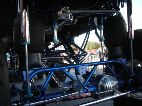1998 Ford Crown Victoria - Underbody view of a custom lifted vehicle showing a blue tubular frame, chrome air-spring suspension and polished differential.