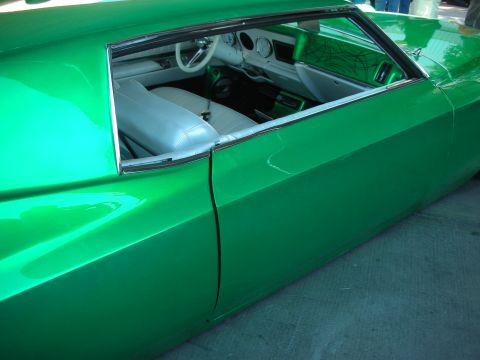 1998 Ford Crown Victoria - Side profile of a glossy green custom car with chopped roofline, white leather seats and a white steering wheel visible through the window.