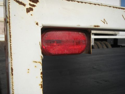 1990 Ford Bronco - Close-up of a red oval trailer light mounted on a white, rusty metal frame.