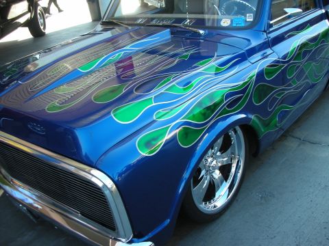 1998 Ford Crown Victoria - Front quarter of a lowered blue custom pickup with elaborate green flame airbrush graphics and a polished five-spoke wheel.