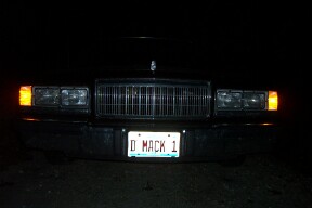 1990 Mercury Grand Marquis - Front view of a black 1990 Mercury Grand Marquis at night, showing its grille and headlights.