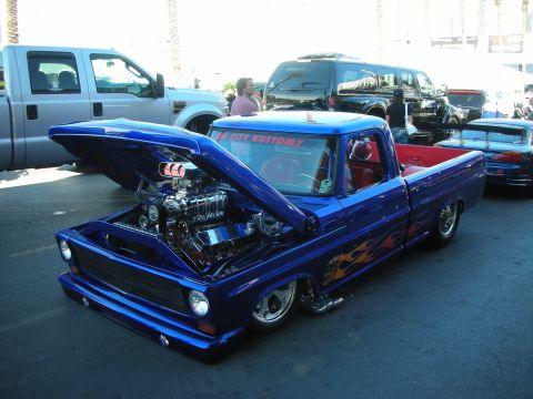1998 Ford Crown Victoria - lowered blue custom pickup with the hood up showing a blown engine with chrome blower, flame side graphics and red interior.