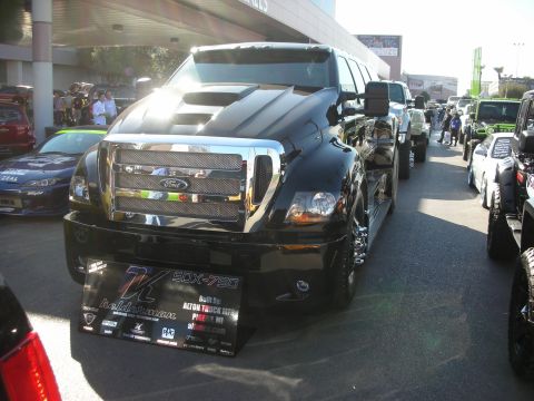 1998 Ford Crown Victoria - black custom Ford medium-duty truck shown head-on with chrome grille and a banner reading SDX-750, parked in a row of show vehicles.