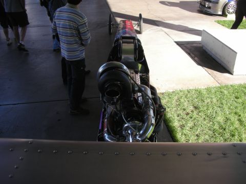 1998 Ford Crown Victoria - Spectators view the rear of a long slingshot-style dragster chassis fitted with a large exposed turbocharger.