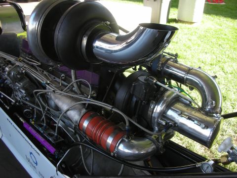 1998 Ford Crown Victoria - Close-up of a large turbocharger, polished piping and a red silicone coupler on the exposed engine of a dragster.