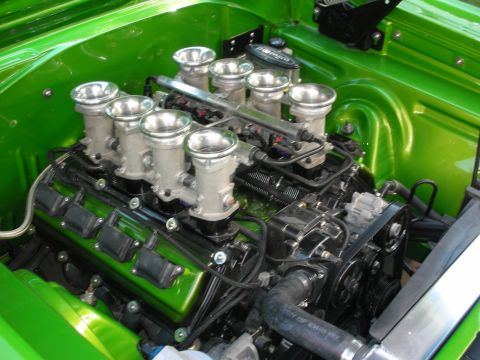 1998 Ford Crown Victoria - V8 engine fitted with eight individual polished velocity-stack throttle bodies sits in the green engine bay of a custom car.
