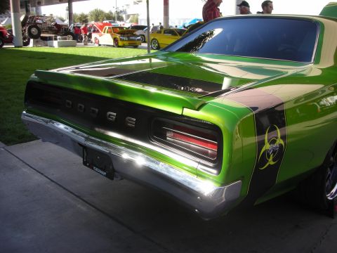 1998 Ford Crown Victoria - Rear three-quarter of the green Dodge muscle car showing chrome DODGE lettering on the tail panel and a yellow biohazard decal.