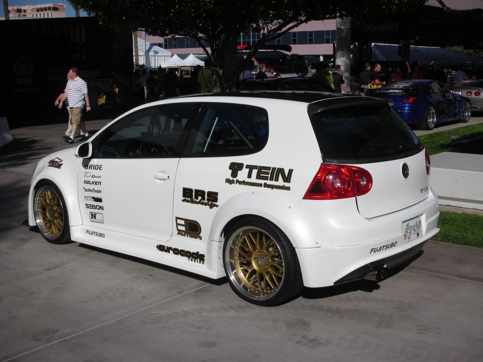 White Volkswagen Golf hatchback with gold wheels and sponsor decals