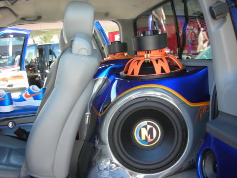 1998 Ford Crown Victoria - custom car-audio install showing a large Memphis subwoofer and an orange driver mounted in a blue painted enclosure behind gray leather sea…