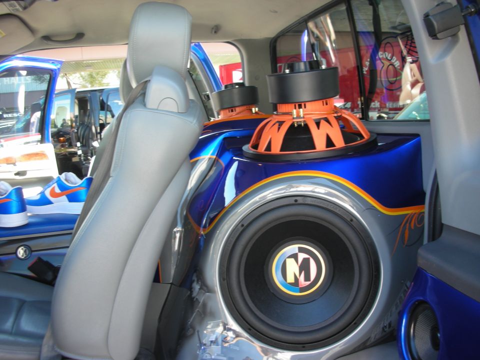 Custom blue car audio install with orange Memphis subwoofer mounted behind the seats