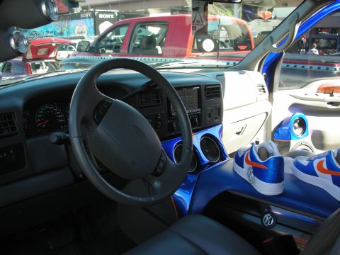 1998 Ford Crown Victoria - Interior of a Ford truck with a blue-accented dash and console; a pair of blue and orange sneakers rests on the passenger seat.