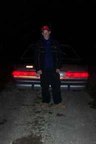 1990 Mercury Grand Marquis - A person stands before the rear of a sedan at night, with the 'SUPERMOTORS' logo visible at the bottom.