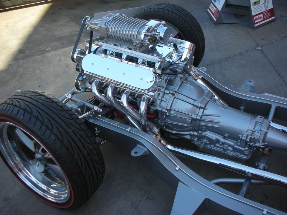 Polished supercharged V8 engine mounted on a bare chassis with staggered wheels