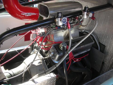 1998 Ford Crown Victoria - polished V8 race engine with Edelbrock valve covers, red spark-plug wires and aluminum bodywork in an open engine bay.