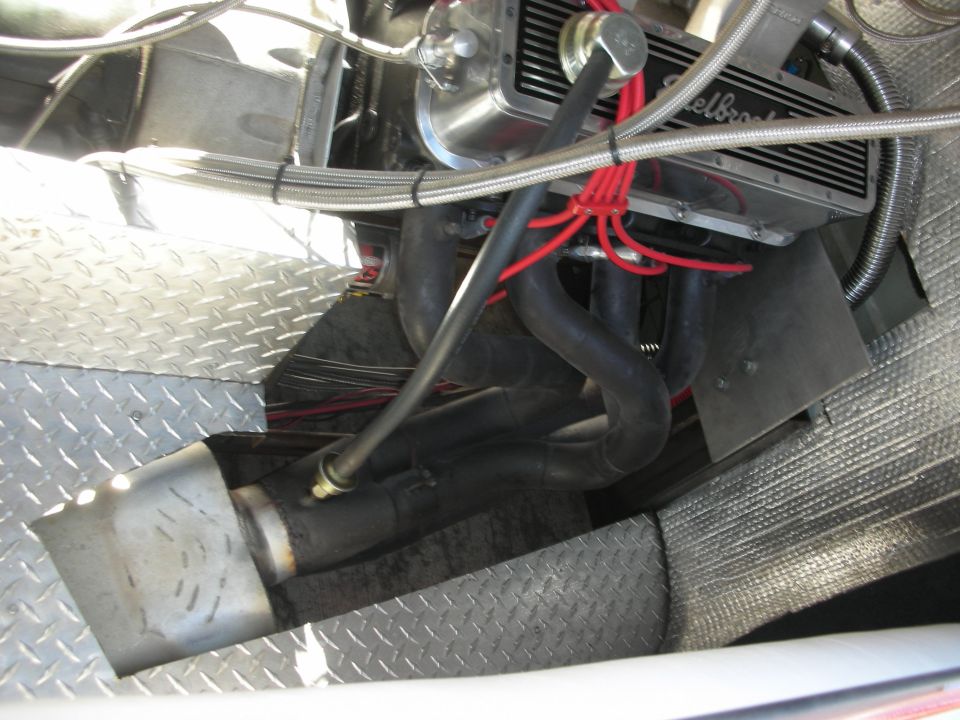 Underside engine detail with black exhaust headers, braided lines and diamond-plate floor