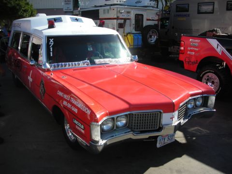 1998 Ford Crown Victoria - red and white vintage ambulance-style station wagon lettered for Chino Hills Transmission, parked at an outdoor event.