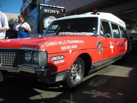 1998 Ford Crown Victoria - Front three-quarter view of a red ambulance-style wagon with chrome wheels and Chino Hills Transmission and Lincoln Electric graphics.