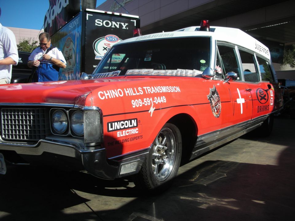 Front of red Chino Hills Transmission ambulance wagon with chrome wheels and sponsor logos