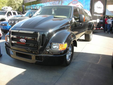 1998 Ford Crown Victoria - large black Ford F-650 crew-cab pickup with mesh grille and chrome wheels displayed at an outdoor event.