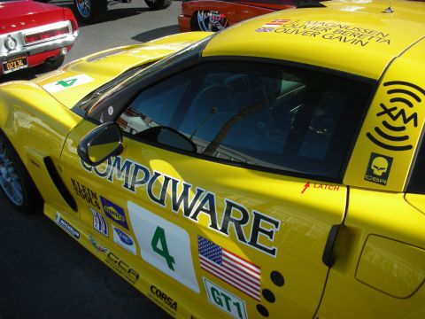 1998 Ford Crown Victoria - Side view of a yellow Chevrolet Corvette GT1 race car with Compuware livery, a US flag and number 4 door graphic.