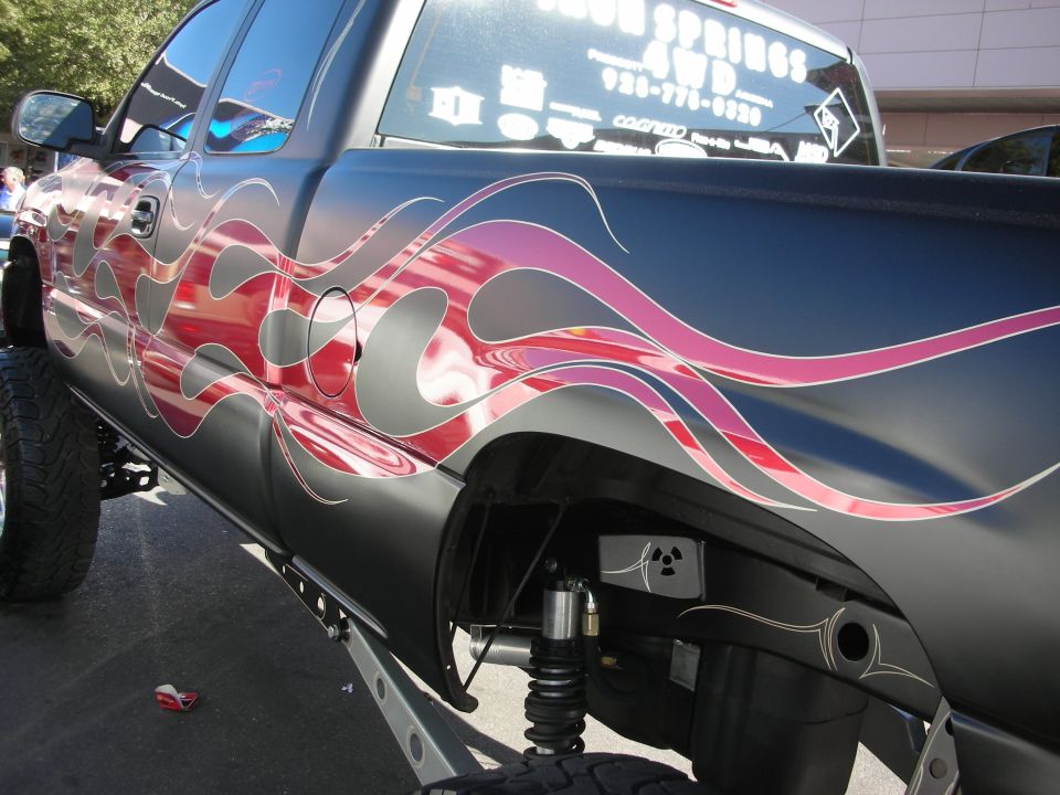 Side bed detail of black pickup with red and purple flame airbrush graphics