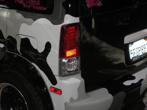 1998 Ford Crown Victoria - Close-up of a camo-wrapped wagon's rear corner with a red LED taillight and a California license plate.