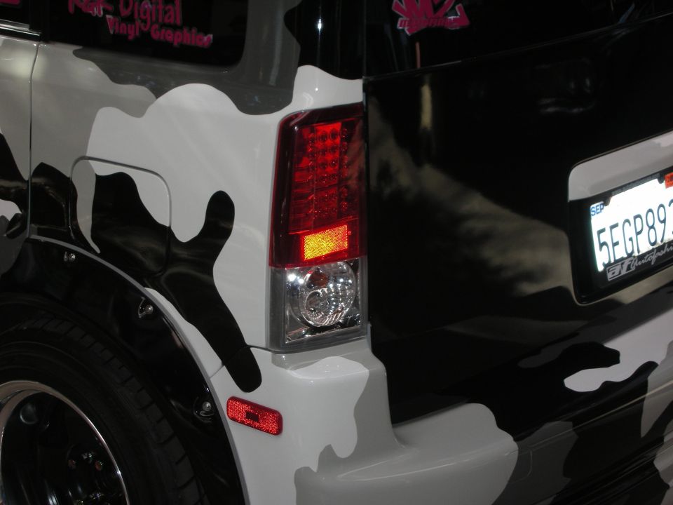 Rear corner of camo-wrapped wagon showing LED taillight and California license plate