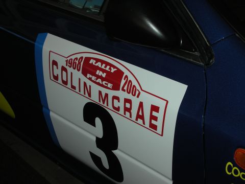 1998 Ford Crown Victoria - blue rally car door carries a white tribute decal reading 'Rally in Peace Colin McRae 1968 2007' with race number 3.