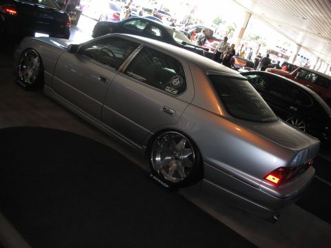 1998 Ford Crown Victoria - silver lowered luxury sedan on chrome wheels with Dunlop tire markers, viewed from the rear quarter indoors.
