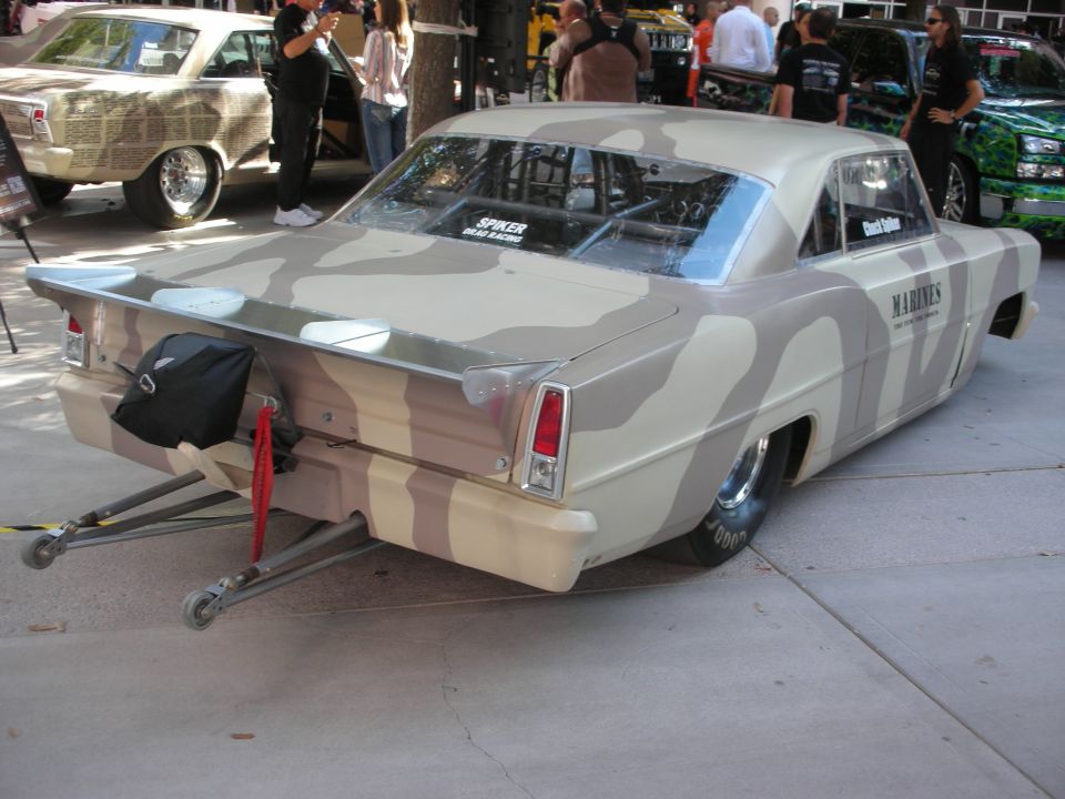 Tan and brown camo-painted drag car with wheelie bars and Marines decal at show
