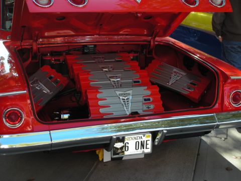 1998 Ford Crown Victoria - open trunk of a red classic car displays rows of gray amplifiers above a Nevada plate reading '6 ONE'.