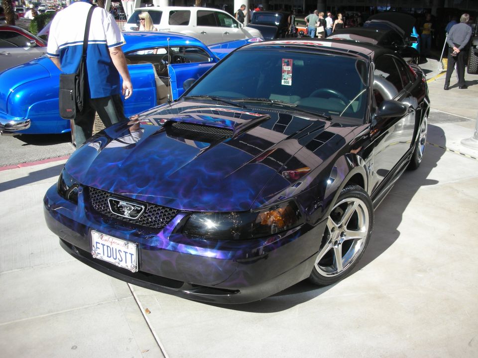 Black Ford Mustang with purple flame paint and ETDUST plate at outdoor car show