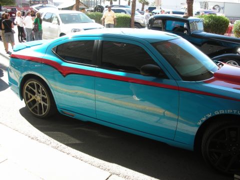 1998 Ford Crown Victoria - Profile of a light blue Dodge Charger with red and chrome wave graphics and bronze wheels parked at an outdoor car show.