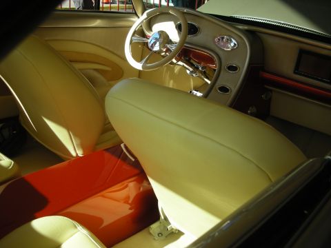 1998 Ford Crown Victoria - Interior of a custom car showing cream leather bench seats, a chrome banjo steering wheel and bright orange floor panels.