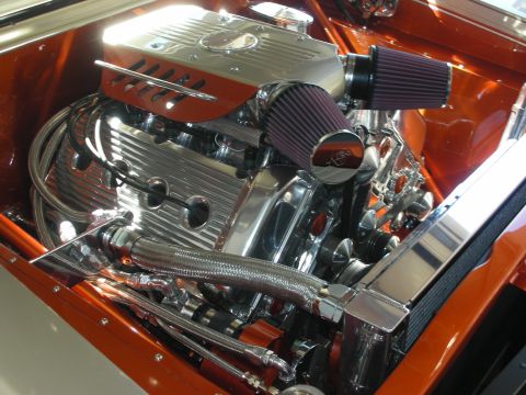 1998 Ford Crown Victoria - highly polished chrome V8 engine fitted with cone air filters and braided lines, mounted in an orange custom car's bay.