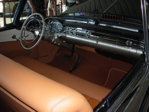 1998 Ford Crown Victoria - Interior of a vintage car showing a large two-spoke steering wheel, chrome dashboard and tan leather upholstery with brown carpet.