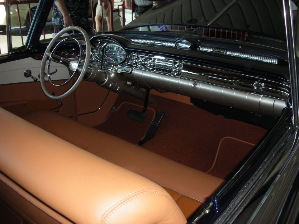 Vintage car interior with large steering wheel, chrome dash and tan upholstery