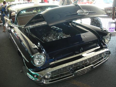 1998 Ford Crown Victoria - dark blue chopped 1950s-style custom hardtop with a heavy chrome grille and open hood revealing a polished engine, shown outdoors.