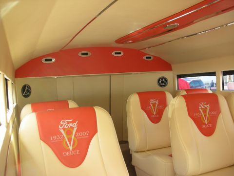 1998 Ford Crown Victoria - Interior of a custom vehicle showing cream leather seats embroidered with a Ford V8 Deuce 1932-2007 logo under a red and cream curved roof.