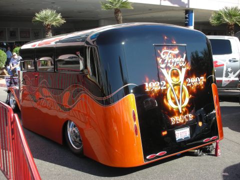 1998 Ford Crown Victoria - Rear three-quarter view of a lowered black and orange custom bus with flame graphics and a flaming Ford V8 Deuce 1932-2007 rear logo.